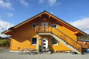 A wooden house with a balcony, a staircase, and a door.