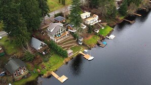 An aerial view of a lakeside property with multiple buildings, docks, and boats. - Modern Lakefront home, 3 bds, 2 baths, dock, gazebo, kayaks, and fishing. (Stanwood)