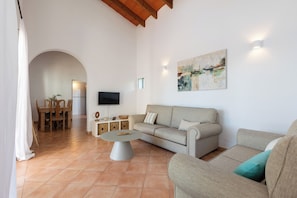 Ein Wohnzimmer mit einer Couch, einem Couchtisch, einem Fernseher und einem Gemälde an der Wand.