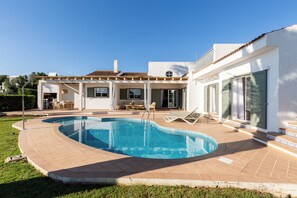 Ein Haus mit Swimmingpool, Gartenmöbeln und einer Terrassenfläche.