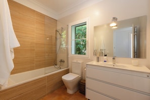 A bathroom with a bathtub, toilet, and sink. - Vrbo Property (Sant Lluís)