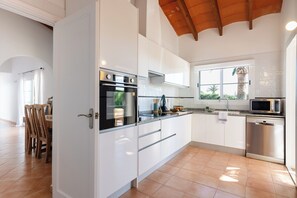Eine moderne Küche mit weißen Schränken, einem Backofen, einer Mikrowelle und einem Geschirrspüler.