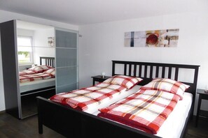 Ein Schlafzimmer mit einem Bett, einem Nachttisch, einem Spiegel und einem Kleiderschrank.