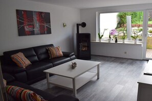 Ein modernes Wohnzimmer mit einer schwarzen Couch, einem weißen Couchtisch und einem Kamin.