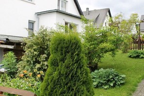 Ein Wohnhausgarten mit verschiedenen Pflanzen und einer hölzernen Bank.