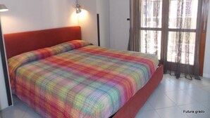 A bedroom with a bed, a nightstand, a lamp, and a window with curtains. - Cozy Vacation Home With Lovely Views in Grado (Grado)