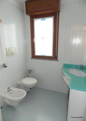 Ein kleines Badezimmer mit Toilette, Bidet und Waschbecken.