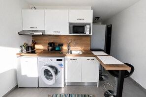 A compact kitchen with a washing machine, microwave, and coffee maker. - Cosy studio, magnificent swimming pool with exceptional view of the Gulf of St-Tropez (Roquebrune-sur-Argens)
