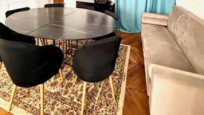 A room with a round table, black chairs, a grey sofa, a patterned rug, and a framed photo on the wall. - Champs Elysées  190 m2 - 8 personnes -Exceptionnel Appartement Haussmannien (Paris)