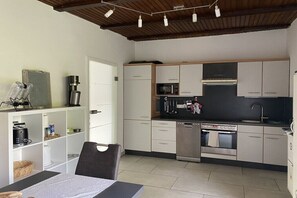 Eine kompakte Küche mit modernen Geräten, eine Essecke mit Tisch und Stühlen sowie eine Decke mit freiliegenden Balken.