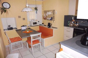 A compact kitchen with a dining table, chairs, a microwave, a kettle, and a coffee maker. - Holiday apartment with 2 bedrooms (Enkirch)