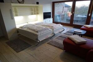 A bedroom with a bed, a TV, a sliding glass door to a balcony, and a red chair. - Sea eagle 22 in Tossens (Butjadingen- Tossens)