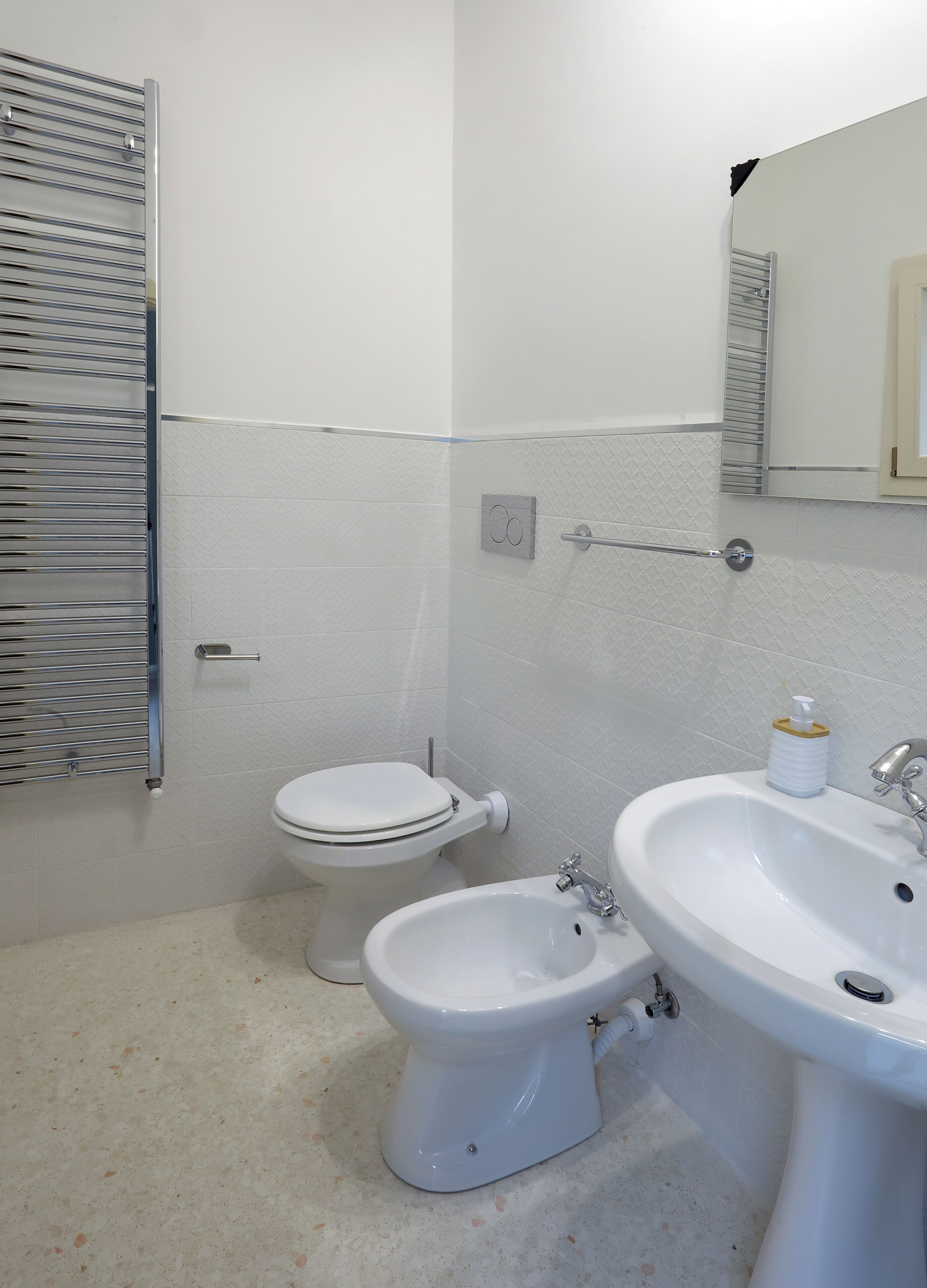 Un baño con inodoro, lavabo, espejo, toallero y bidé.