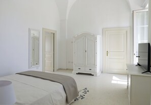 Ein Schlafzimmer mit Bett, Kleiderschrank, Spiegel und Fernseher.