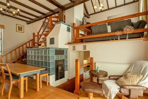 A cozy room with a wooden staircase, a fireplace, a dining table, and a comfortable seating area.