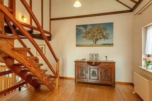 A wooden staircase, a cabinet with decorative handles, and a painting of a tree on the wall.