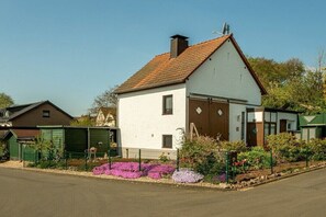 Een gelijkvloers huis met een schuin dak, een garage en een omheinde tuin met bloemen.