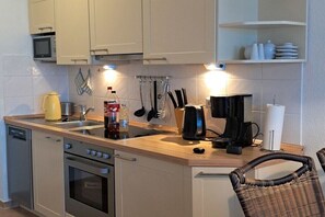 Eine kleine Küche mit Mikrowelle, Kaffeemaschine und Wasserkocher.