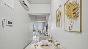 Une chambre d’hôtel moderne dotée d’un coin repas, offrant une vue sur la ville, et ornée d’une grande œuvre d’art décorative représentant une feuille sur le mur.