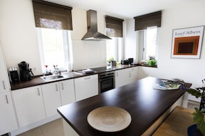 Een moderne keuken met witte kastjes, een donker aanrecht, een groot eiland en een hangende lamp.