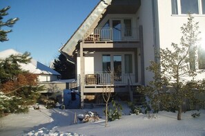 Een gebouw met twee verdiepingen, een balkon op de bovenste etage, een met sneeuw bedekte grond en een heldere lucht.