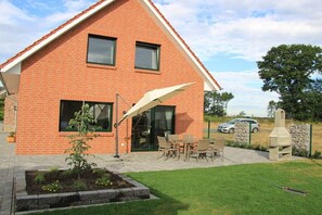 A brick house with a patio, outdoor seating, and a barbecue area. - Holiday home with 4 bedrooms (Niedersachsen - Garrel)