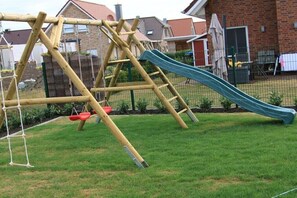 A wooden playground structure with a slide and swings. - Holiday home with 4 bedrooms (Niedersachsen - Garrel)