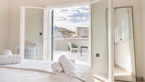 Habitación de hotel con cama, baño y balcón con vista a edificios y una cúpula azul.