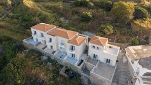 Un edificio de varios pisos con tejado de tejas, rodeado de paisaje natural.