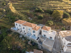 A multi-story building with a tiled roof, surrounded by natural landscape.