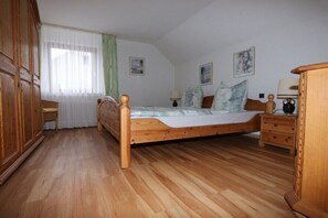 Ein Schlafzimmer mit einem Holzbett, einem Nachttisch, einem Kleiderschrank und einem Fenster mit Vorhängen.