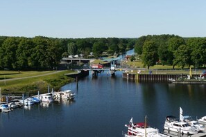 A marina with boats docked, a bridge, and a forested area in the background. - Holiday home in Trebel with swimming pool (Trebel)