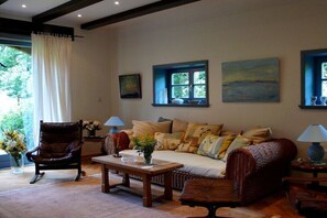 A living room with a sofa, armchairs, a coffee table, and a window with a view of trees. - Holiday home in Trebel with swimming pool (Trebel)