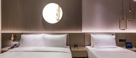 Habitación de hotel con dos camas, un espejo redondo, una mesita de noche con teléfono y una lámpara de pared.
