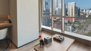A modern room with a large window, a desk, a chair, and a vase with a flower. - Crystal Hotel Qingdao MixC Shandong Road (Qingdao)
