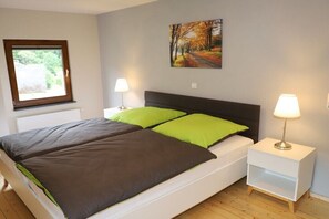Ein Schlafzimmer mit einem Bett, zwei Nachttischen, einem Fenster und einem Bild an der Wand.