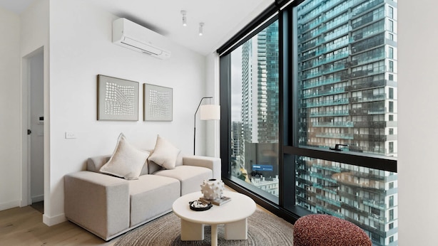 Una sala de estar moderna con un sofá, una mesa de centro y un ventanal con vistas a la ciudad.