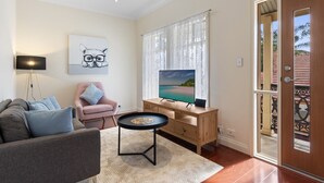 A living room with a sofa, a chair, a coffee table, a TV, and a door leading outside. - Family-Friendly 4-Bed Home with Parking (Seacombe Gardens)