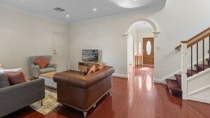 A living room with a sofa, armchair, and coffee table. There is a door and a staircase in the background. - Family-Friendly 4-Bed Home with Parking (Seacombe Gardens)
