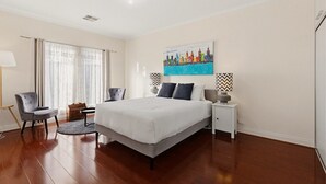 A bedroom with a bed, two chairs, a nightstand, a lamp, and a painting on the wall. - Family-Friendly 4-Bed Home with Parking (Seacombe Gardens)