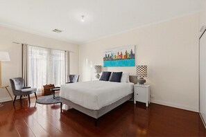 A bedroom with a bed, two chairs, a nightstand, a lamp, and a painting on the wall. - Family-Friendly 4-Bed Home with Parking (Seacombe Gardens)