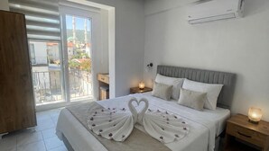 Et soveværelse med seng, et natbord, et træskab, en balkon med udsigt og en aircondition.