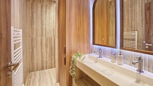 Une salle de bain moderne avec un meuble-lavabo en bois, un grand miroir et un espace douche.