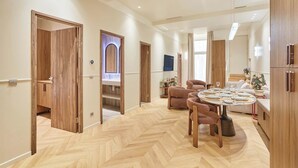 Un vaste espace de vie doté d’un parquet en chevrons, de portes en bois, d’une table à manger ronde et d’un canapé.