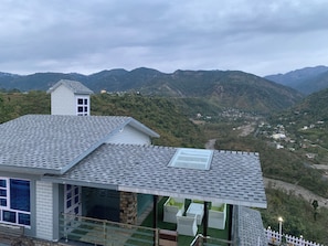 Un edificio moderno con techo inclinado, ventanas amplias y vista a un valle con montañas.