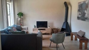 A living room with a sofa, a chair, a TV, a fireplace, and a painting on the wall.