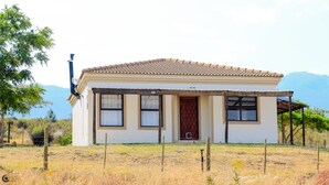 A single-story house with a tiled roof, a wooden door, and a fenced yard.