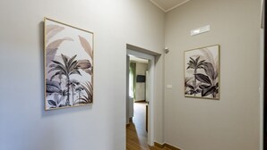 A hallway with two framed botanical prints on the walls, a wooden floor, and a doorway leading to another room. - GuestHost - Cozy Balcony Flat X3 near the Sea (Francavilla al Mare)
