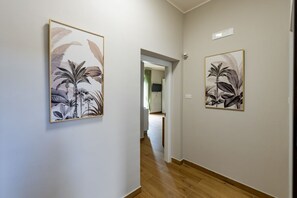 Un corridoio con due stampe botaniche incorniciate alle pareti, pavimento in legno e una porta che conduce in un'altra stanza.