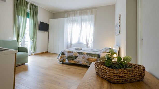 A bedroom with a bed, a sofa, a TV, and a window with curtains. - GuestHost - Cozy Balcony Flat X3 near the Sea (Francavilla al Mare)